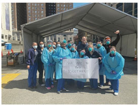 Team of medical workers posing in from of large tent